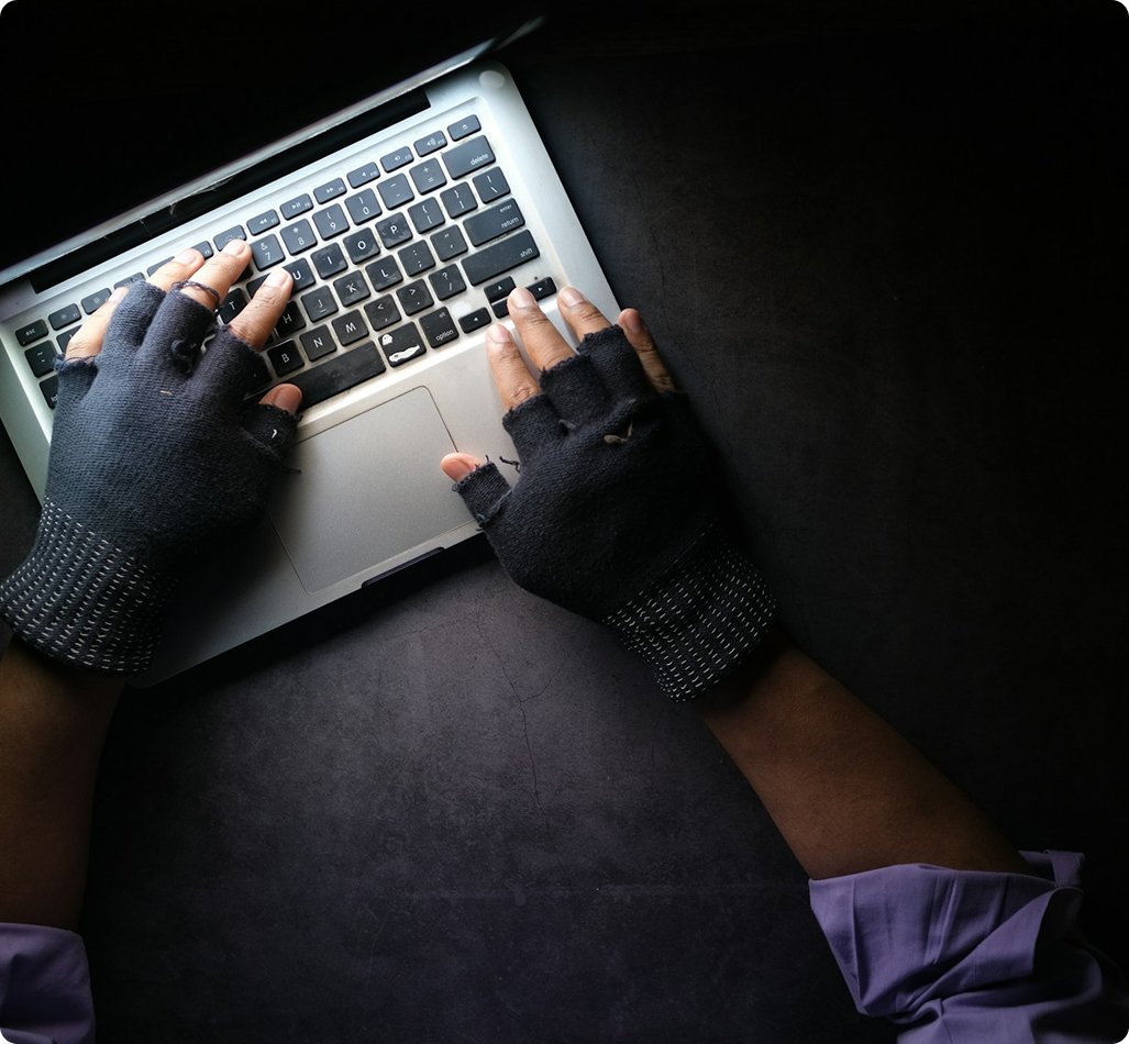 Hands typing on a laptop in a dark workspace